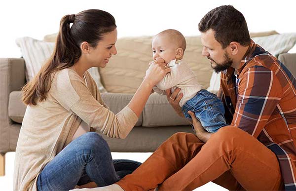 man and woman holding baby sitting on the floor