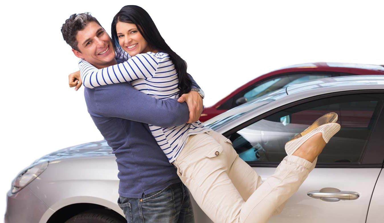 a couple hugging in front of a new car